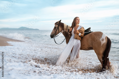 woman in formal dress in ocean with horse, time exposure showing motion of waves photo