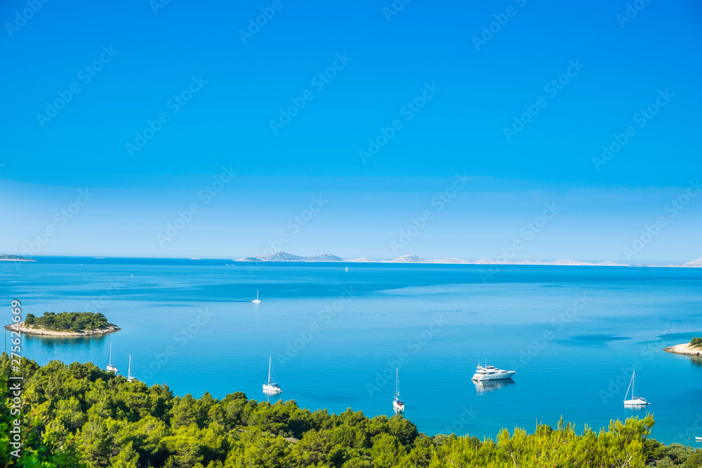 Panoramic view on Kosirina beach bay on Murter island in Croatia, anchored sailing boats and yachts on blue sea