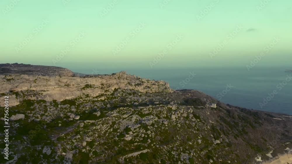 Majestic sunset on Dingli Cliifs. Aerial shot approaching highest point of Malta, Mediterranean sea in the background, foggy day Majestic sunset on Dingli Cliifs. Aerial shot approaching highest point of Malta, Mediterranean sea in the background, foggy day
