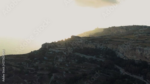 Epic sunset over the Dingli cliffs, direct sunlight and dramatic sky with Morning Glory Clouds, aerial drone dolly in shot photo