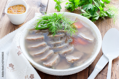 Jellied pork tongue in white bowl on a wooden table, horizontal