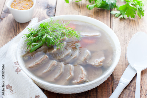 Jellied pork tongue in white bowl on a wooden table, horizontal photo