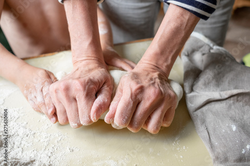 Closeup portrait of kids and adult hands making dough for pastry 