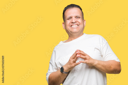 Middle age arab man wearig white t-shirt over isolated background Hands together and fingers crossed smiling relaxed and cheerful. Success and optimistic