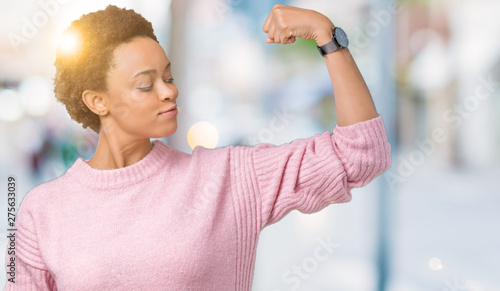 Beautiful young african american woman over isolated background Strong person showing arm muscle, confident and proud of power