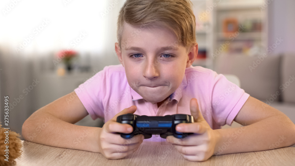 Excited male kid playing video game with console, eyesight problems risk Excited male kid playing video game with console, eyesight problems risk