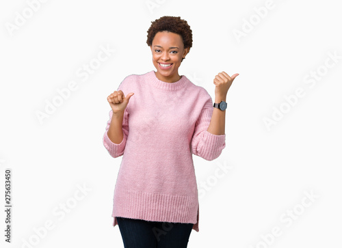 Beautiful young african american woman over isolated background Pointing to the back behind with hand and thumbs up, smiling confident photo