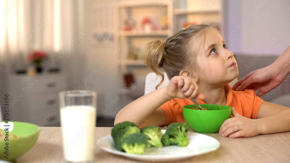 Mom touching girl who eating healthy breakfast, vegetarian lifestyle, broccoli Mom touching girl who eating healthy breakfast, vegetarian lifestyle, broccoli