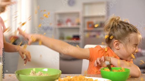 Cuadro en lienzo Happy little boy and girl throwing cornflakes at each other, having fun at home