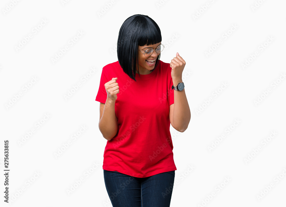 Beautiful young african american woman wearing glasses over isolated background very happy and excited doing winner gesture with arms raised, smiling and screaming for success. Celebration concept. Beautiful young african american woman wearing glasses over isolated background very happy and excited doing winner gesture with arms raised, smiling and screaming for success. Celebration concept.