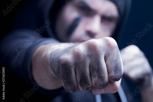 Close up aggressive man giving a punch. Robbery and konflict concept. Selective focus on fist.