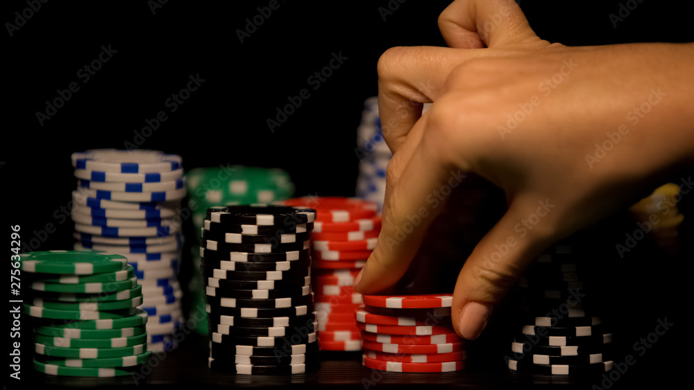 Hand choosing red chip among stacks of tokens, casino game odds, lucky bet Hand choosing red chip among stacks of tokens, casino game odds, lucky bet
