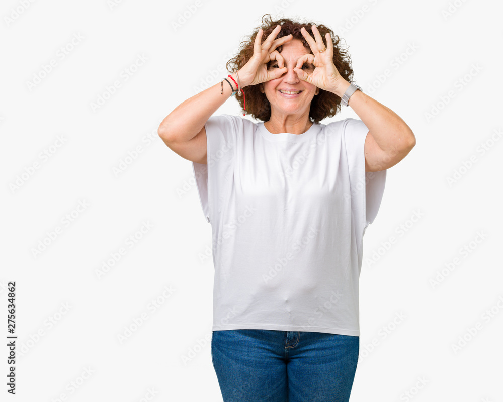 Beautiful middle ager senior woman wearing white t-shirt over isolated background doing ok gesture like binoculars sticking tongue out, eyes looking through fingers. Crazy expression. Beautiful middle ager senior woman wearing white t-shirt over isolated background doing ok gesture like binoculars sticking tongue out, eyes looking through fingers. Crazy expression.