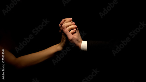 Man in suit and woman holding hands isolated on black background, relationship photo