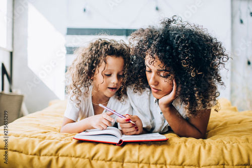 Relaxing woman with daughter writing in notepad