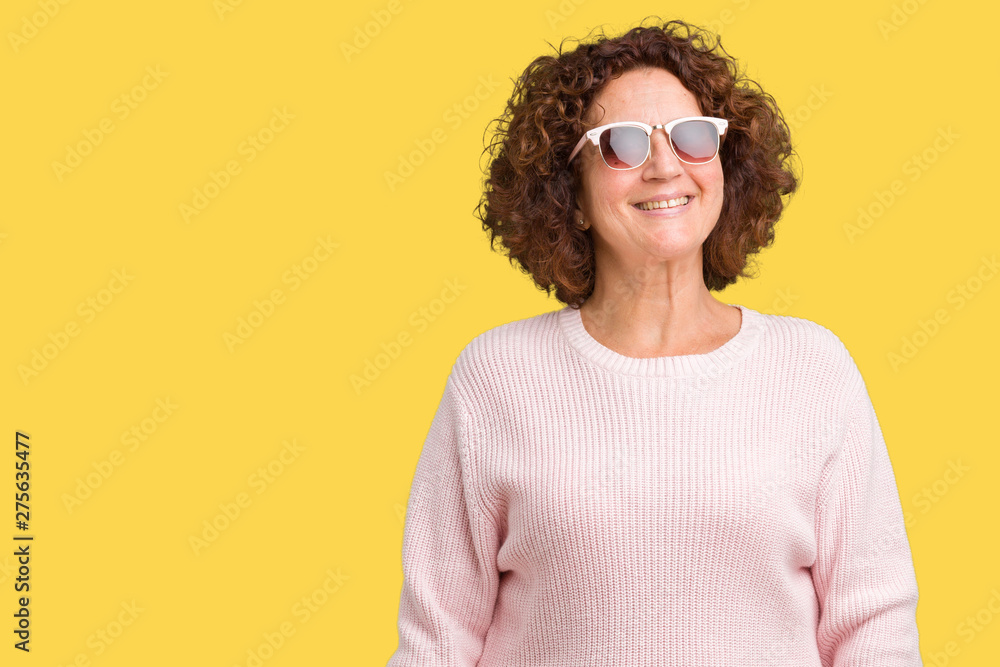 Beautiful middle ager senior woman wearing pink sweater and sunglasses over isolated background smiling looking side and staring away thinking. Beautiful middle ager senior woman wearing pink sweater and sunglasses over isolated background smiling looking side and staring away thinking.