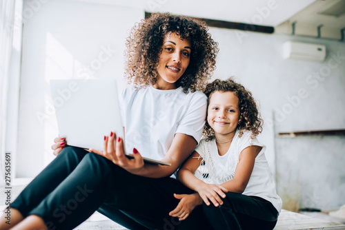Loving mother and daughter sitting with laptop
