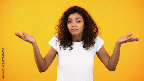 Afro-american female showing no idea gesture, unsure of choice, hesitation photo