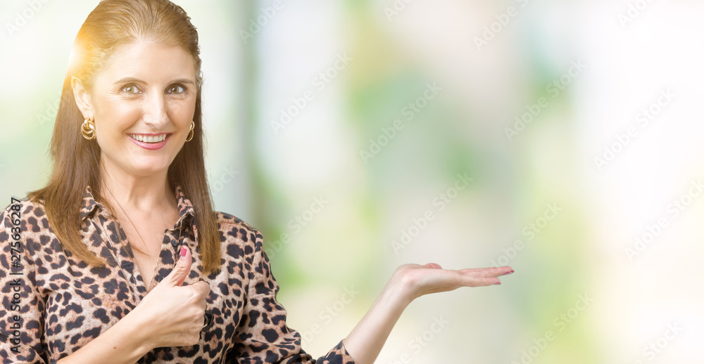 Beautiful middle age mature rich woman wearing leopard dress over isolated background Showing palm hand and doing ok gesture with thumbs up, smiling happy and cheerful Beautiful middle age mature rich woman wearing leopard dress over isolated background Showing palm hand and doing ok gesture with thumbs up, smiling happy and cheerful