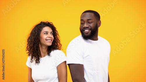 Happy couple flirting and smiling each other on yellow background, acquaintance