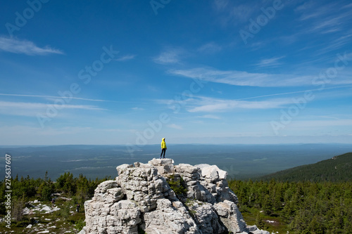 Fototapeta Naklejka Na Ścianę i Meble -  a man in a bright jacket stands on top of a mountain. The scale of the planet. freedom