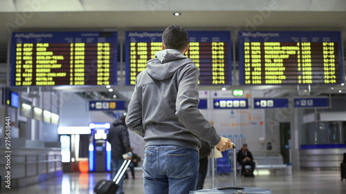 Man traveler looking at time table in train station, preparing for departure photo