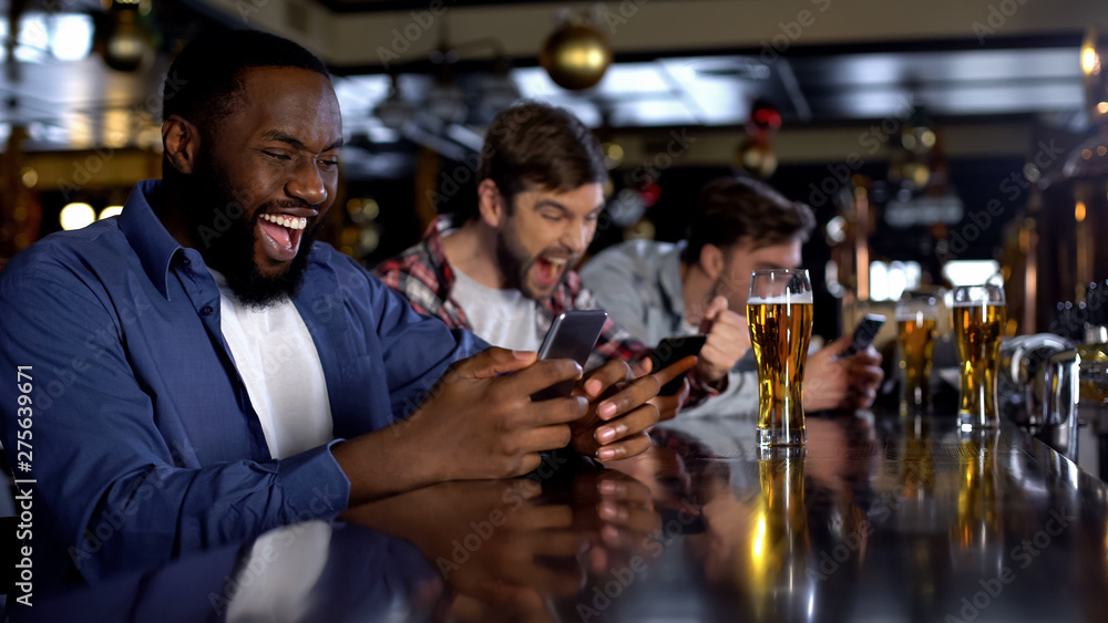 Emotional african-american male celebrating winning bet on match, bookmaker app