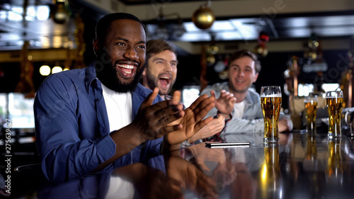 Multiracial male friends celebrating favorite team victory, enjoying time in bar