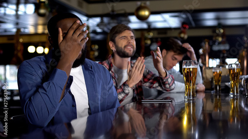 Multiethnic fans watching championship in pub, displeased with losing game