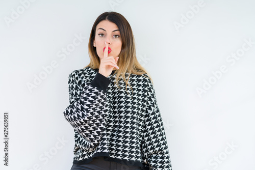 Young woman wearing casual sweater over isolated background asking to be quiet with finger on lips. Silence and secret concept.