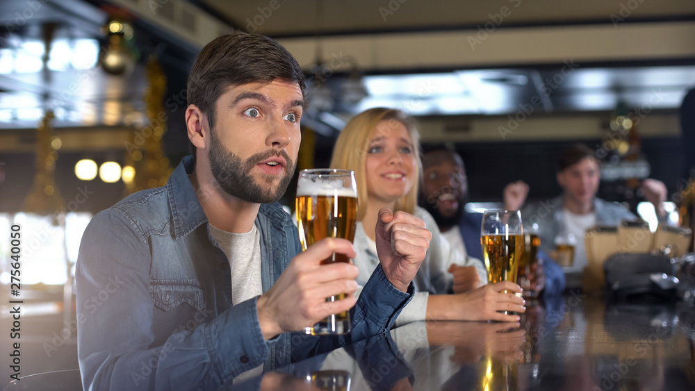 Anxious male cheering for team and holding beer glass, supporting favorite team