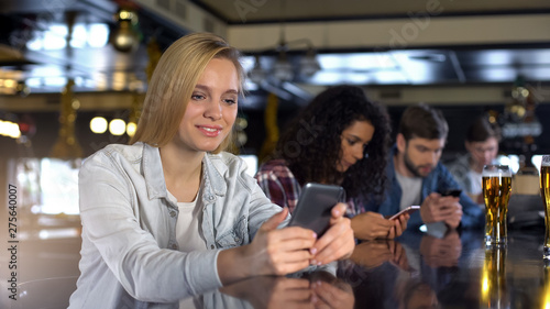 Group of people using phones in bar, addicted to social networks millennials