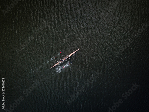 Foto Aerial drone shot af academic rowing team in canoe on dark river