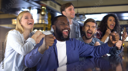 Fotografie Black man with friends supporting sport team, rejoicing winning goal, victory