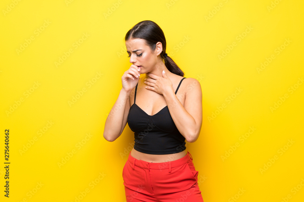 Young woman over isolated yellow background is suffering with cough and feeling bad