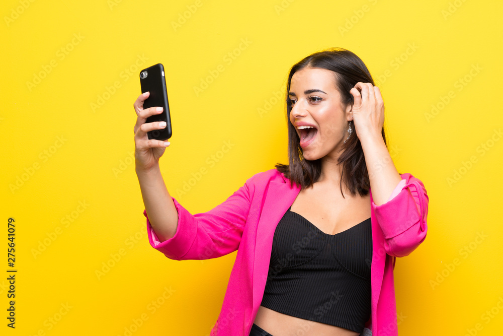 Young woman over isolated yellow background making a selfie Young woman over isolated yellow background making a selfie