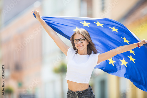 Cute happy young girl with the flag of the European Union in the streets somewhere in europe