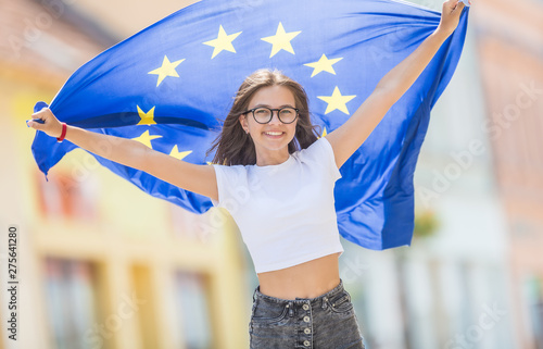 Cute happy young girl with the flag of the European Union in the streets somewhere in europe photo