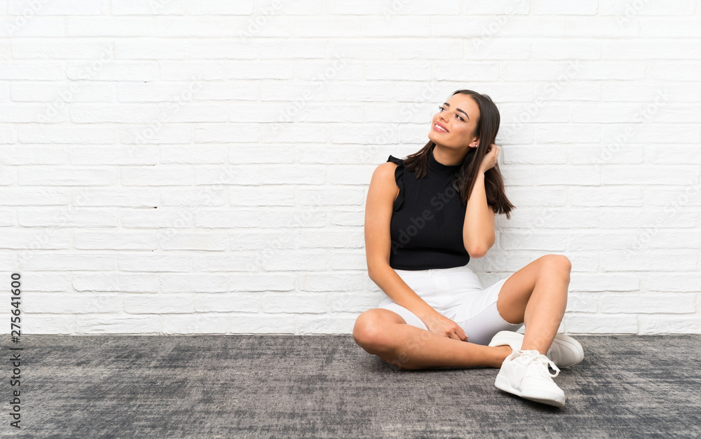 Pretty young woman sitting on the floor thinking an idea Pretty young woman sitting on the floor thinking an idea