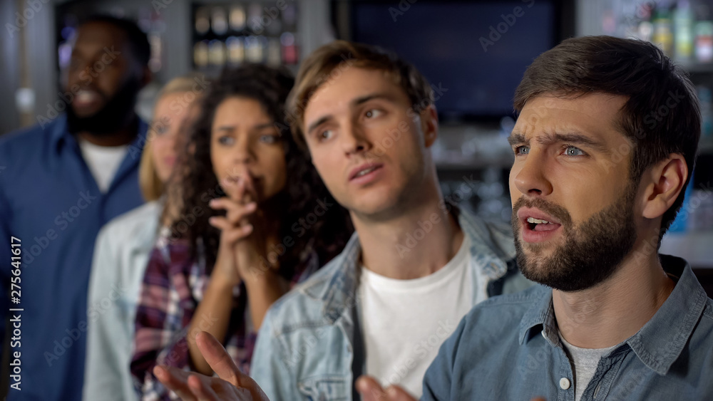 Sad sport fans watching match in bar, young spectators looking disappointed Sad sport fans watching match in bar, young spectators looking disappointed