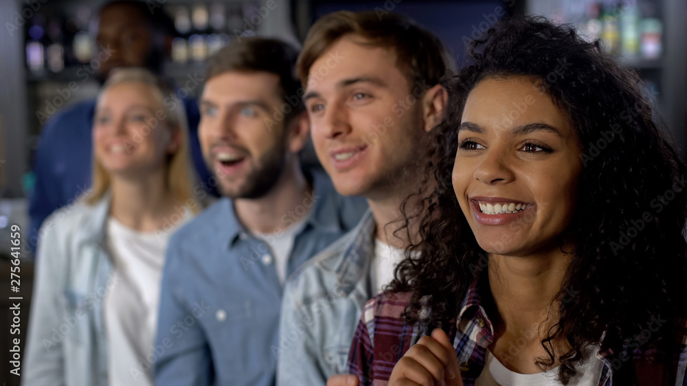 Smiling mixed-race friends rooting for team, watching contest, event audience Smiling mixed-race friends rooting for team, watching contest, event audience