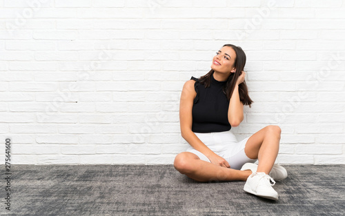 Pretty young woman sitting on the floor thinking an idea