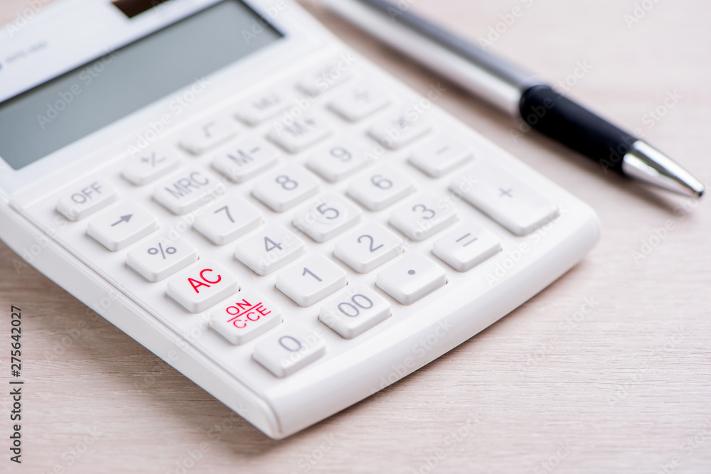 White calculator and pen on bright wooden table, analytics and statistics of financial profit, investment risk concept, copy space, macro, close up White calculator and pen on bright wooden table, analytics and statistics of financial profit, investment risk concept, copy space, macro, close up