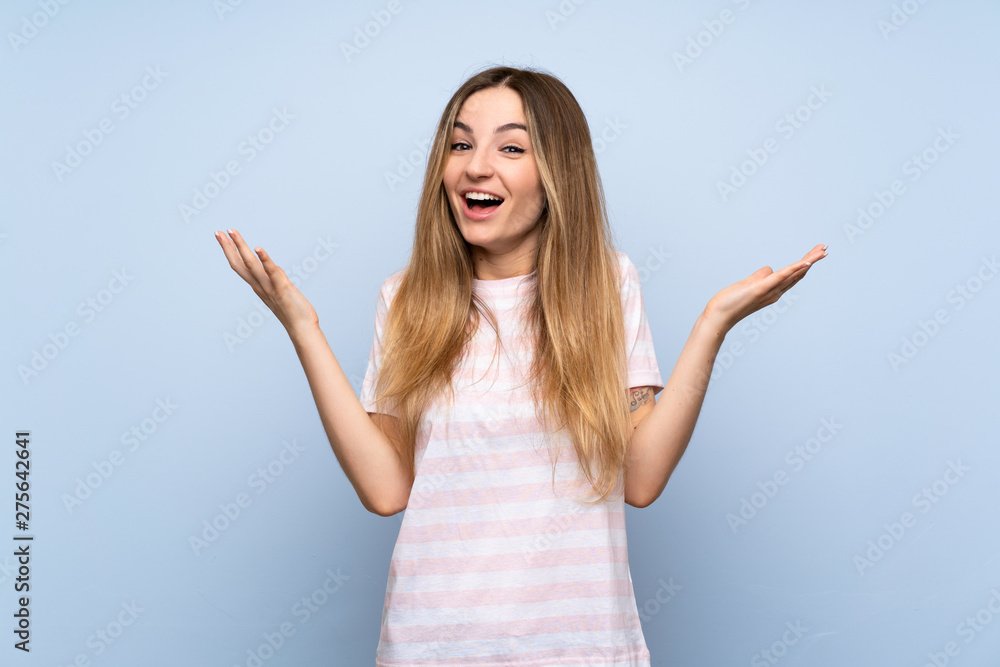 Fototapeta premium Young woman over isolated blue background smiling a lot