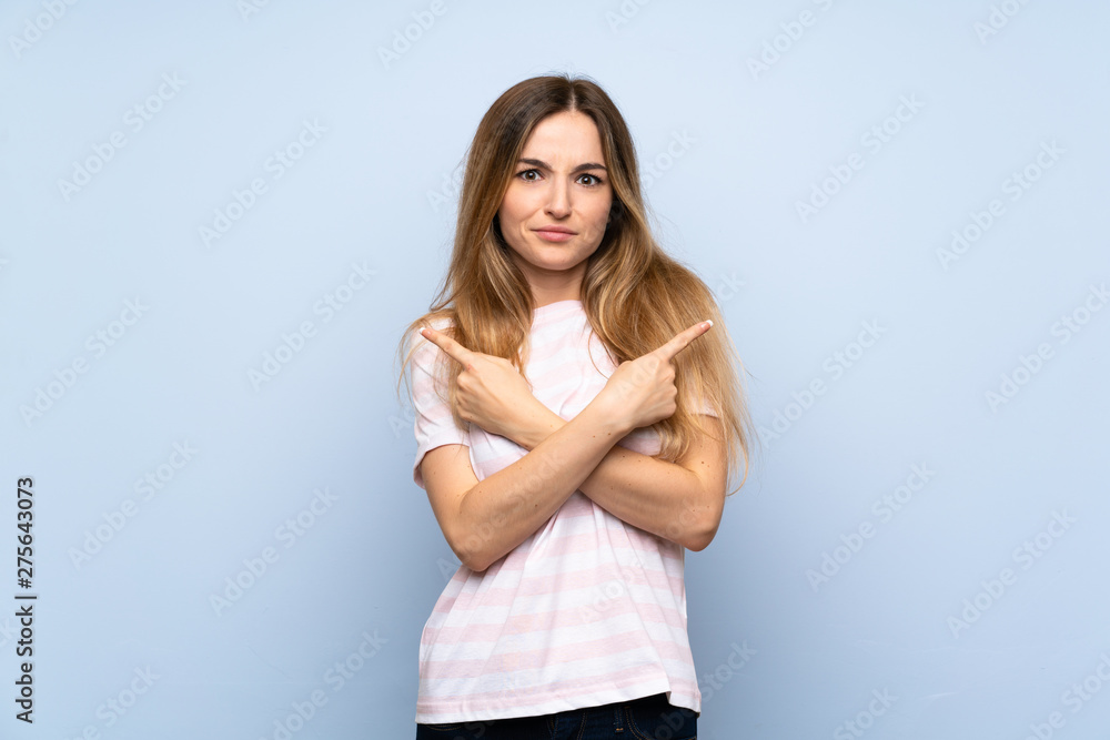 Young woman over isolated blue background pointing to the laterals having doubts Young woman over isolated blue background pointing to the laterals having doubts