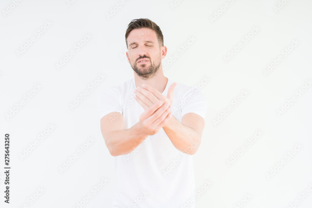Young handsome man wearing casual white t-shirt over isolated background Suffering pain on hands and fingers, arthritis inflammation Young handsome man wearing casual white t-shirt over isolated background Suffering pain on hands and fingers, arthritis inflammation