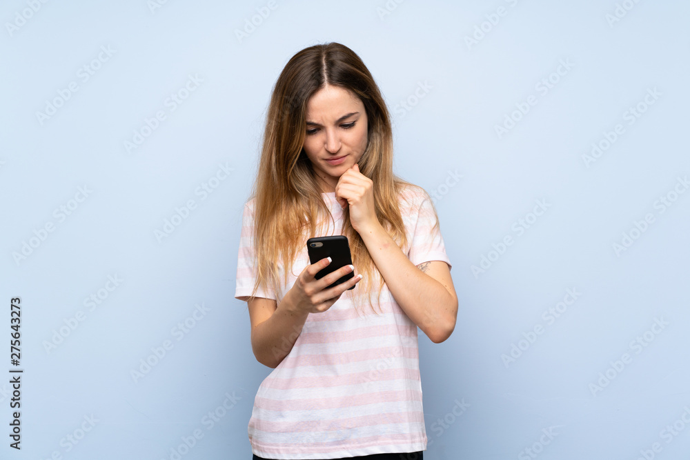 Young woman over isolated blue background thinking and sending a message Young woman over isolated blue background thinking and sending a message