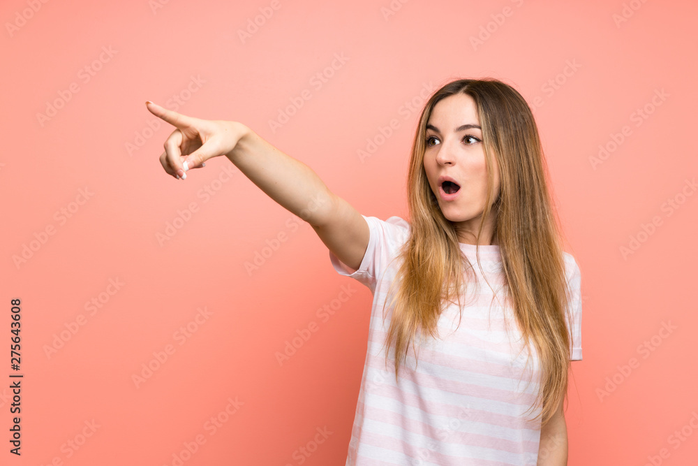 Young woman over isolated pink wall pointing away Young woman over isolated pink wall pointing away