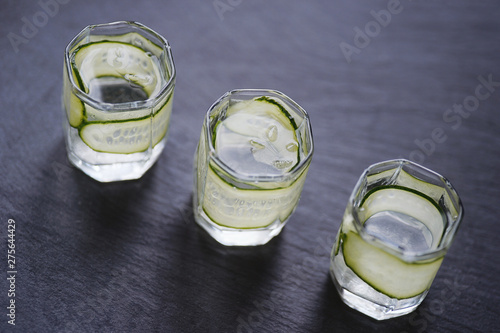 Vodka in shot glasses with cucomber on rustic wood background. photo