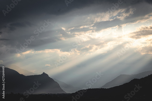 Sun rays pointing on a church on a hill at the entrance of teh val die susa